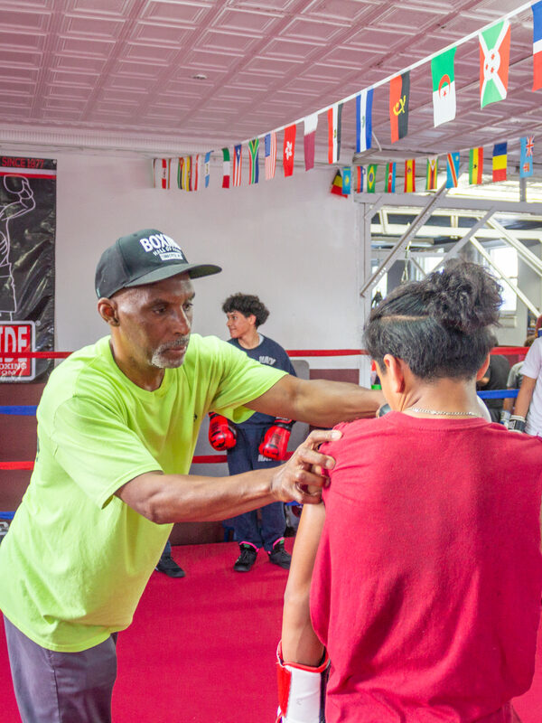A boxing coach guides a young boxer in the ring