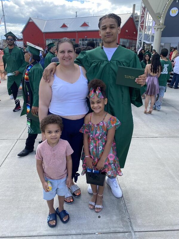 A graduate in a green cap and gown with his family