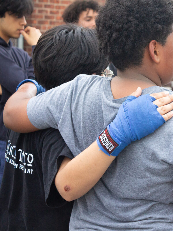 Two young people hug, seen from behind